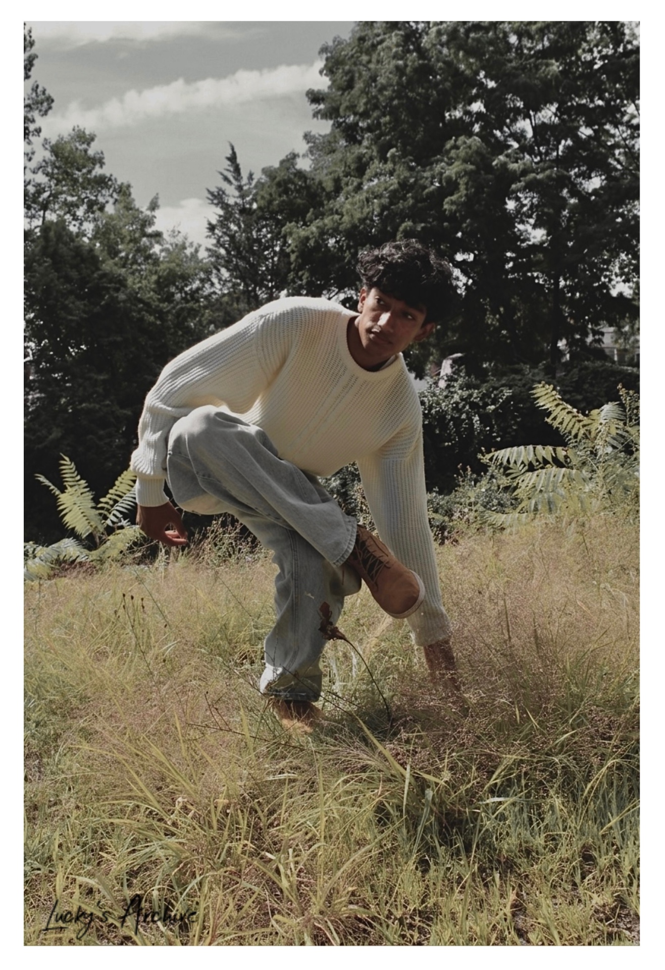 Low-angle editorial portrait crouched in a meadow