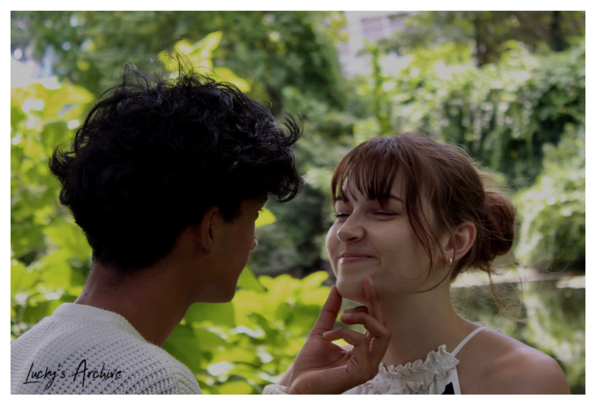Playful moment with a hand on her chin by the water