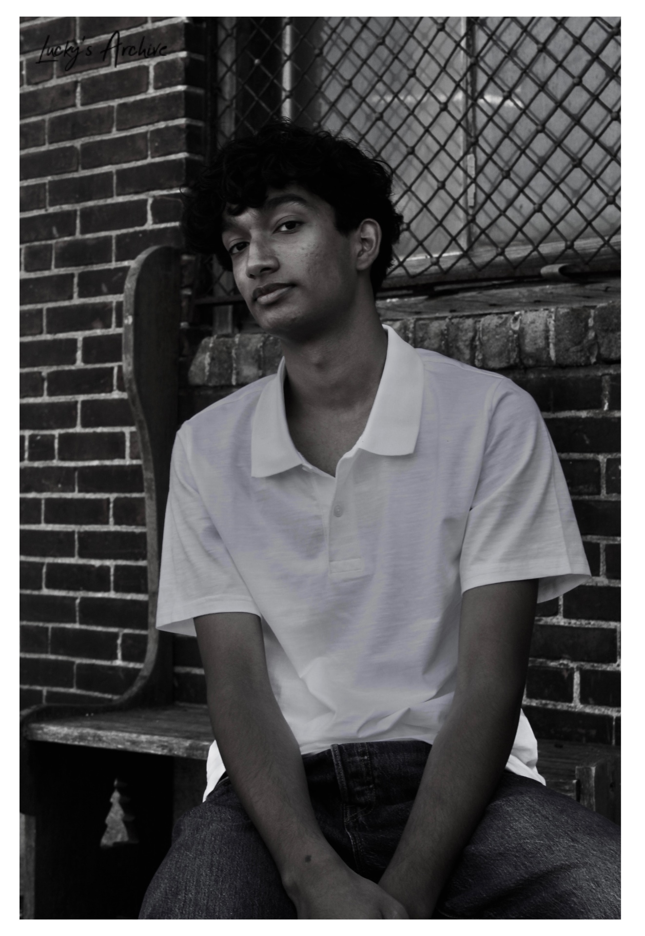 Black and white portrait seated against a brick wall