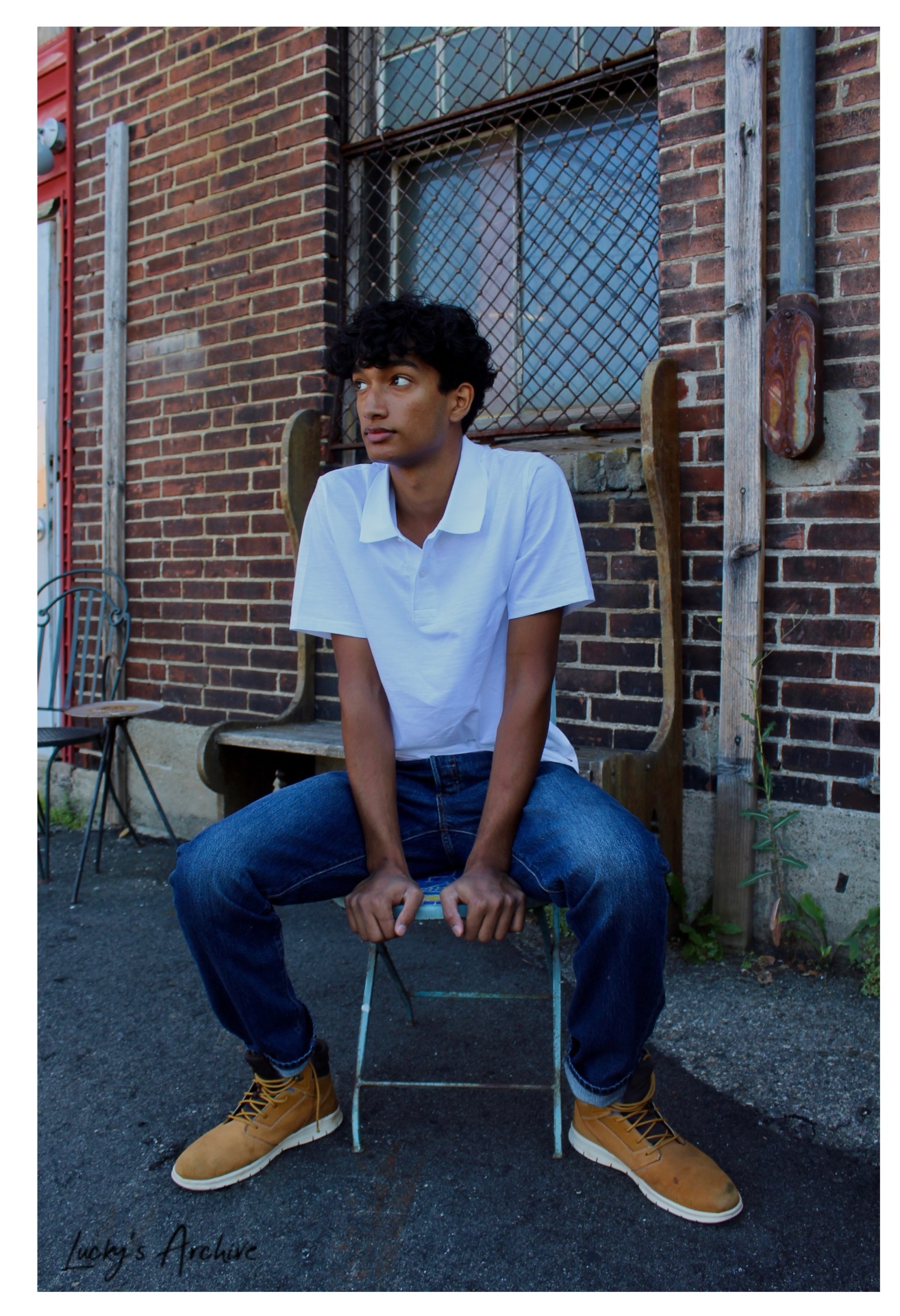 Portrait seated on a chair against a brick wall
