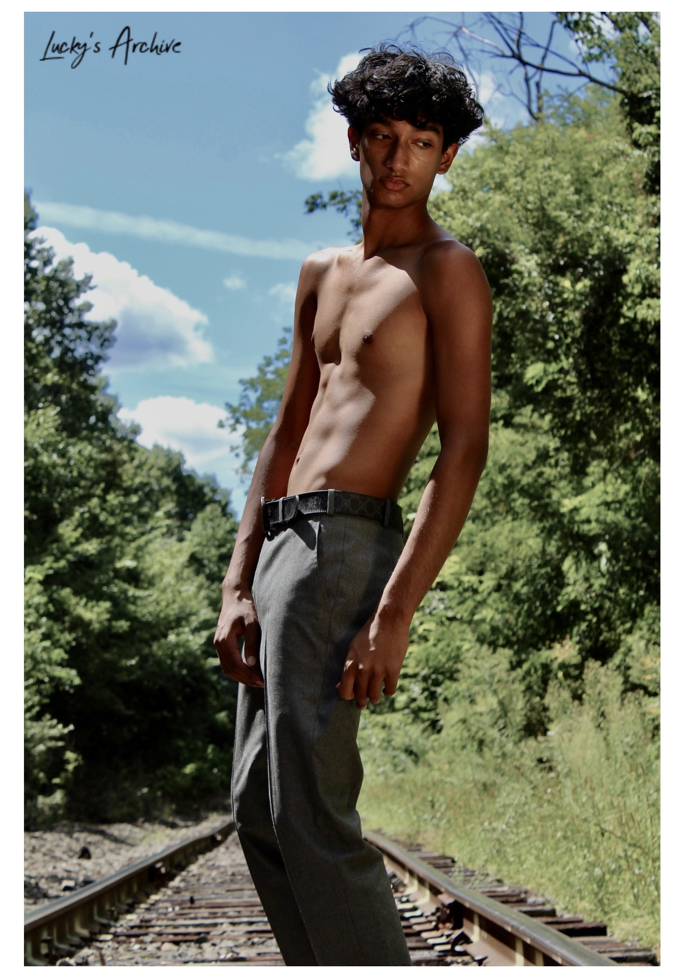 Portrait standing on railroad tracks under a blue sky