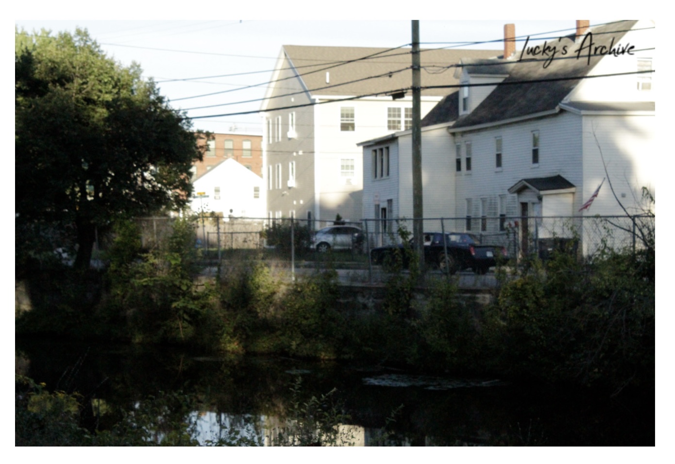 Tennessee mill houses seen across a pond behind a chain-link fence