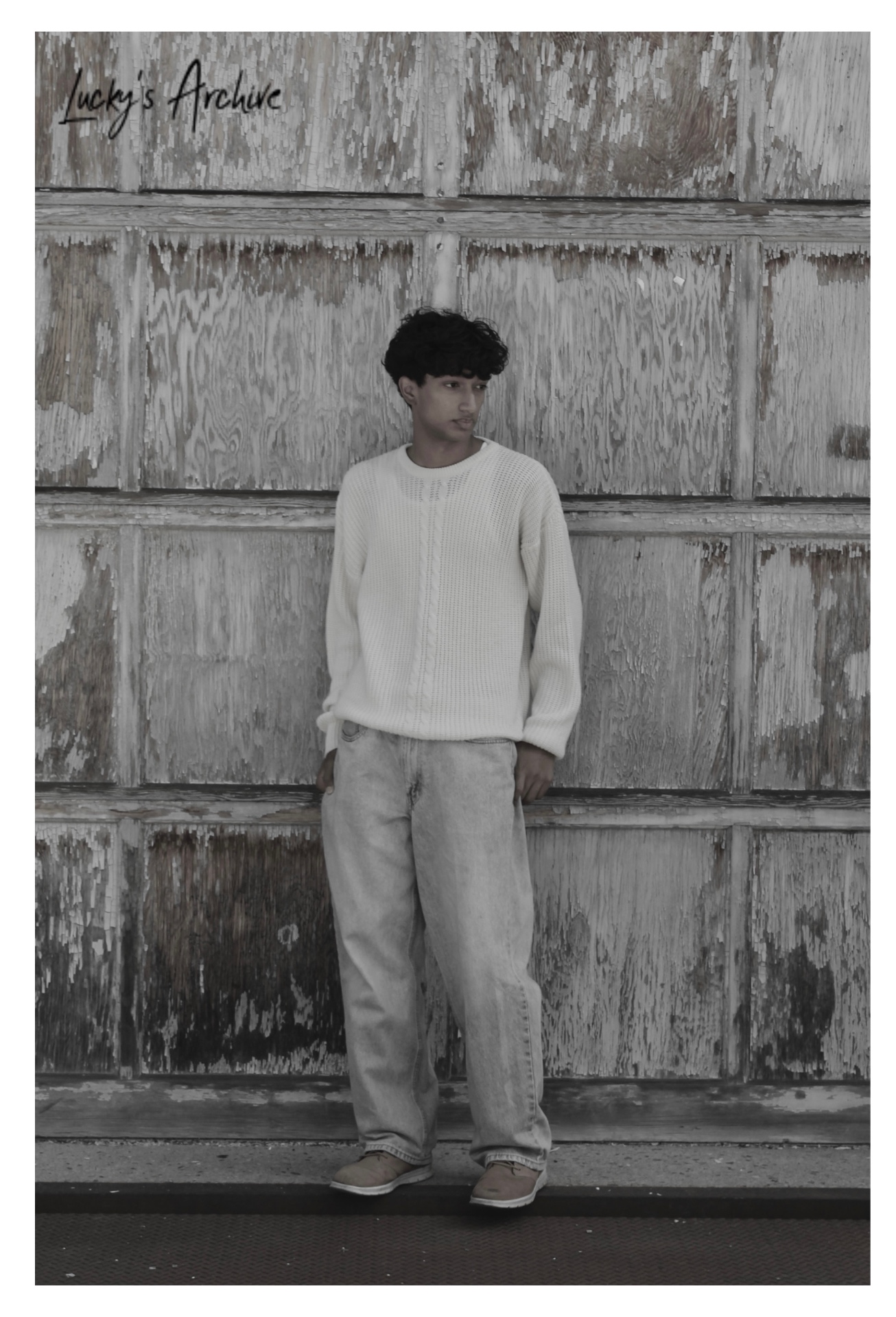 Desaturated full-length portrait against a peeling wood wall