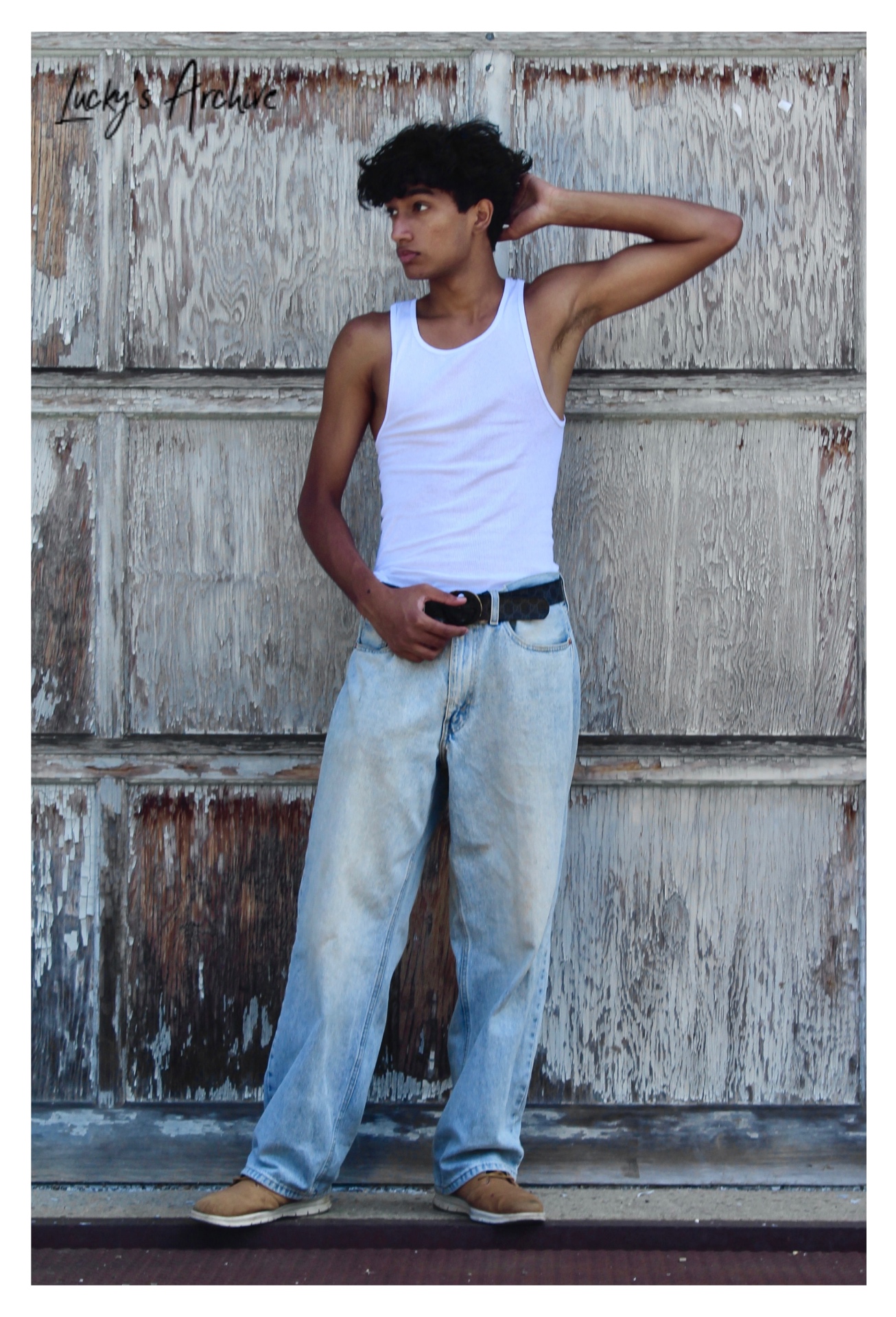 Portrait in a white tank top leaning on a weathered wall